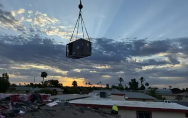 A photo of a crane lifting an HVAC unit into place